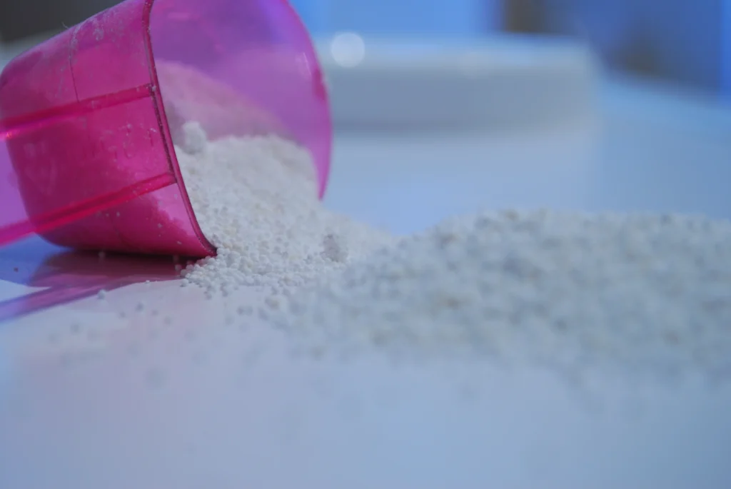 Fine white powder spilling from a measuring scoop